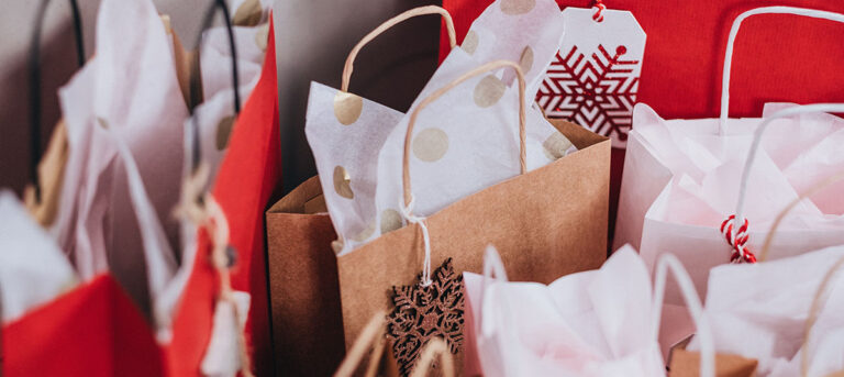 A collection of colorful gift bags ready for the holiday season, with holiday shopping safety tips in mind to protect your purchases.